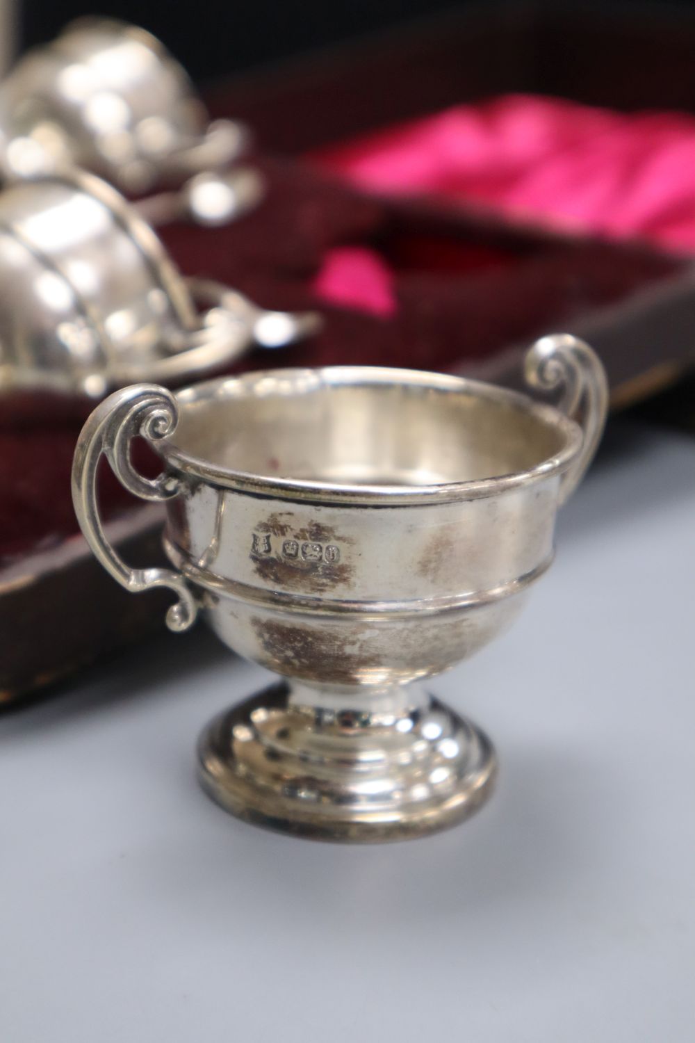 A cased set of four late Victorian silver salts, of two handled trophy cup form and matching spoons,